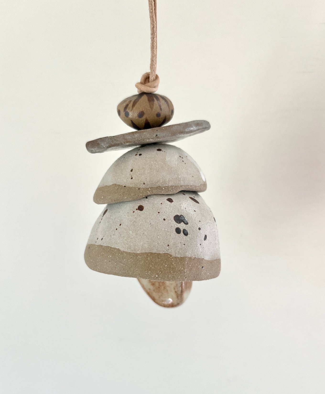 Ceramic bells. Each little bead and bell, unique. A mix of clay bodies and glazes with leather cord for hanging.   May they be a reminder of all the support around you. Each piece unique and made with love. Hand built, glazed and fired in Slo, Ca. 