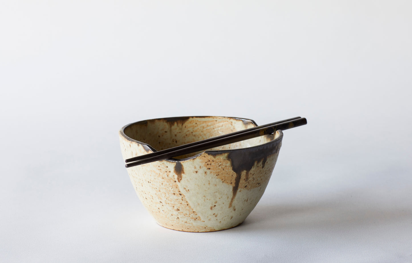 The Luna Collection is crafted from brown stoneware clay and glaze in a satin matte with bronze accent at the lip. Each item is hand thrown. This bowl is perfect noodles or rice. Each dish has two nooks for your chopsticks to rest. Crafted in Lakewood, OH by Gina DeSantis.