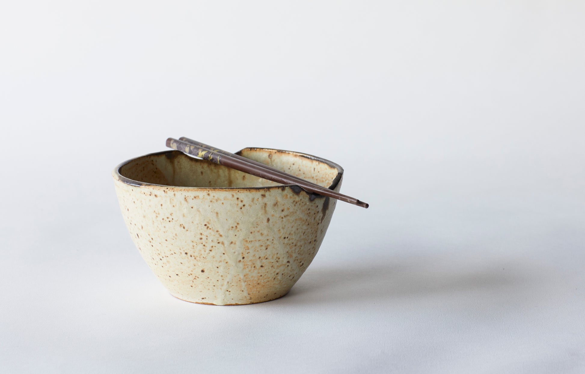 The Luna Collection is crafted from brown stoneware clay and glaze in a satin matte with bronze accent at the lip. Each item is hand thrown. This bowl is perfect noodles or rice. Each dish has two nooks for your chopsticks to rest. Crafted in Lakewood, OH by Gina DeSantis.