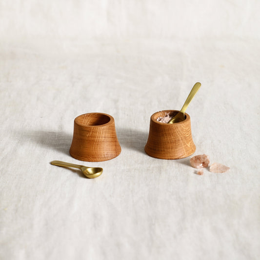 Premium French oak is shaped by hand into these tower-shaped pinch bowls, which are just right for offering salt and pepper or other condiments on the table.

Includes a pair of diminutive matte brass spoons for serving.