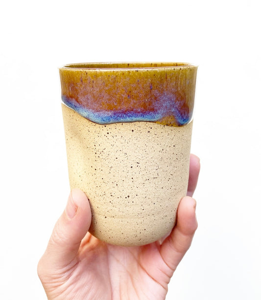 Hand thrown speckled tumbler with a thumb dimple.  Amber interior glaze, with blue and purple variations. Crafted from stoneware & made in Virginia, USA by Korai Ceramics.