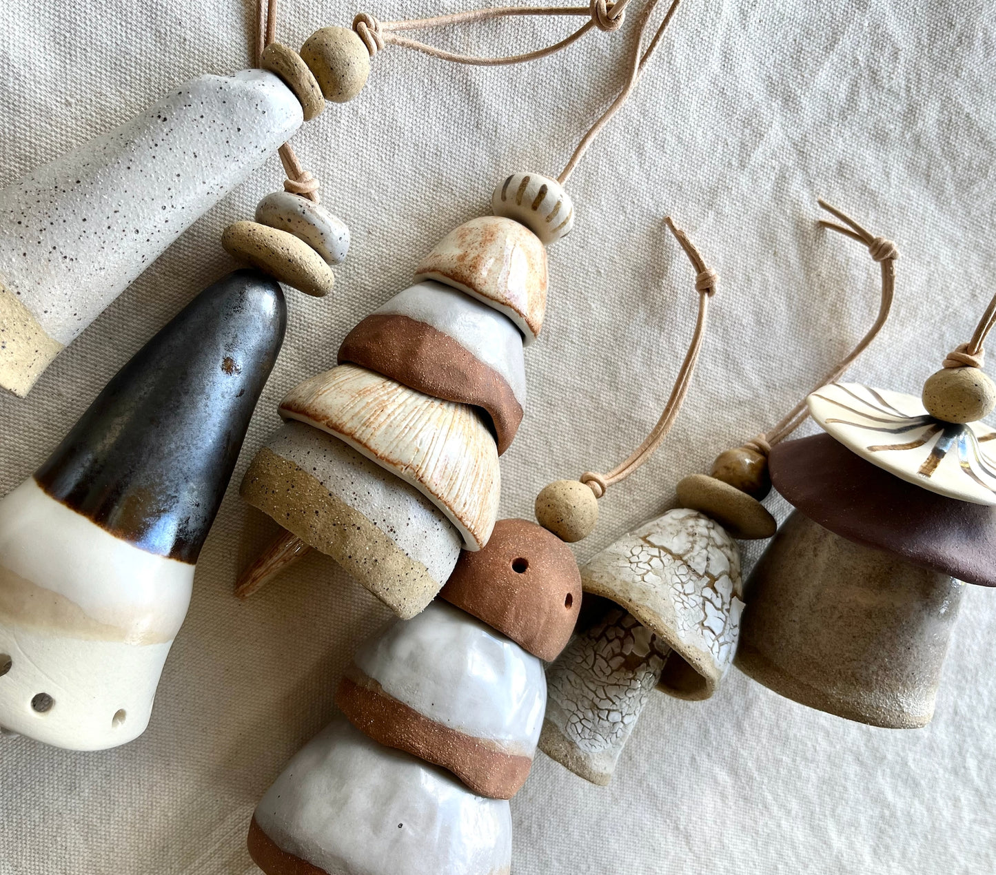 Ceramic bells. Each little bead and bell, unique. A mix of clay bodies and glazes with leather cord for hanging.   May they be a reminder of all the support around you. Each piece unique and made with love. Hand built, glazed and fired in Slo, Ca. 