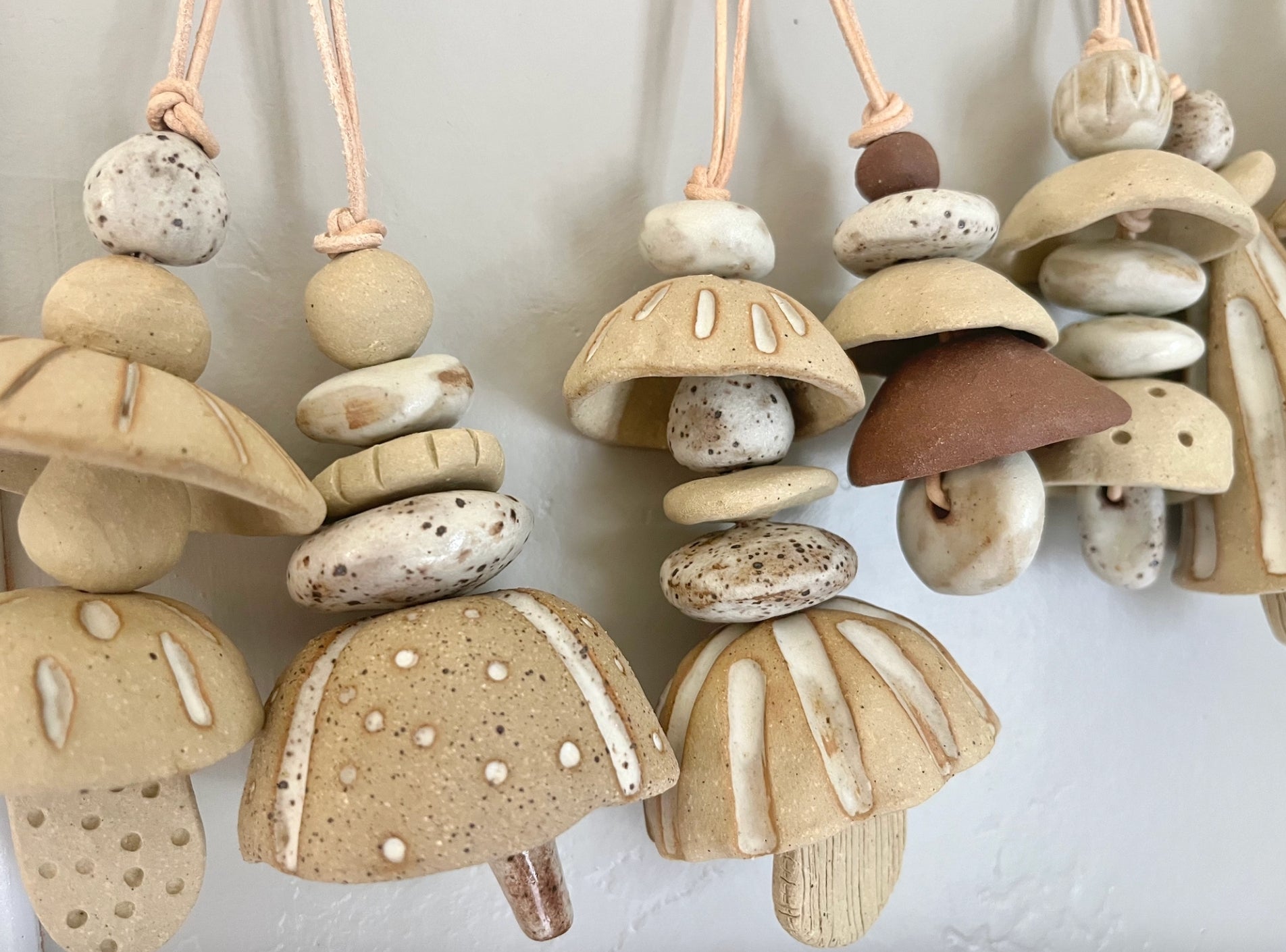 Ceramic bells. Each little bead and bell, unique. A mix of clay bodies and glazes with leather cord for hanging.   May they be a reminder of all the support around you. Each piece unique and made with love. Hand built, glazed and fired in Slo, Ca. 