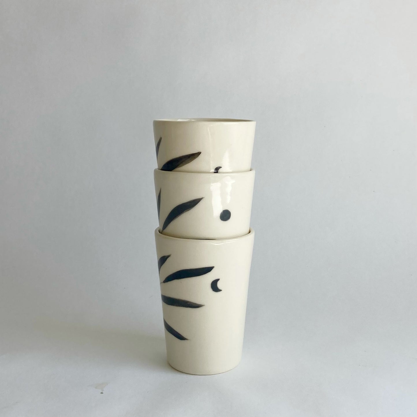 Slip casted ceramic cups in dover white (off white) and painted with black underglaze. Each cup is a little different. Some have full and some have a crescent moon. Handmade by Alicja in her Vermont studio.