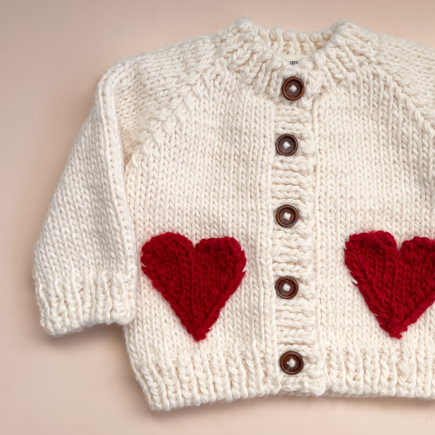 Your baby needs this chunky Cream cardigan with Red faux heart pockets. Perfect for a Valentine's Day outfit or just every day sweetness. Crafted with care using 100% Hand-knit Acrylic