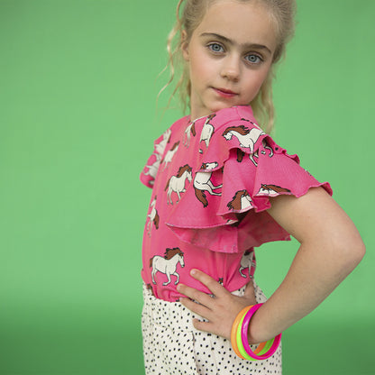 A pink top printed with horses - round neck with ruffle shoulders for fluid movement. Ethically produced, colorful and fun with an eye towards comfort, style and joy. Modern and sustainable kids clothing by CarlijnQ of the Netherlands.