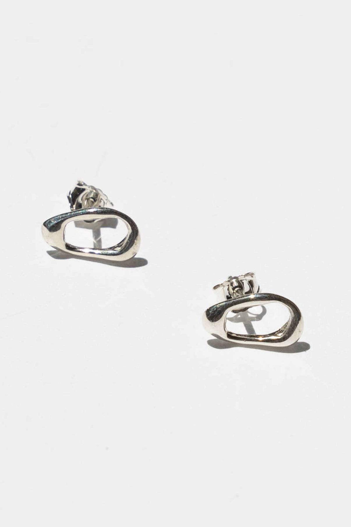 The Current studs are inspired by the dancing shapes you see when sunlight shines on moving water.    Hand carved and cast with a high polished mirror finish. Available in solid brass or sterling silver.