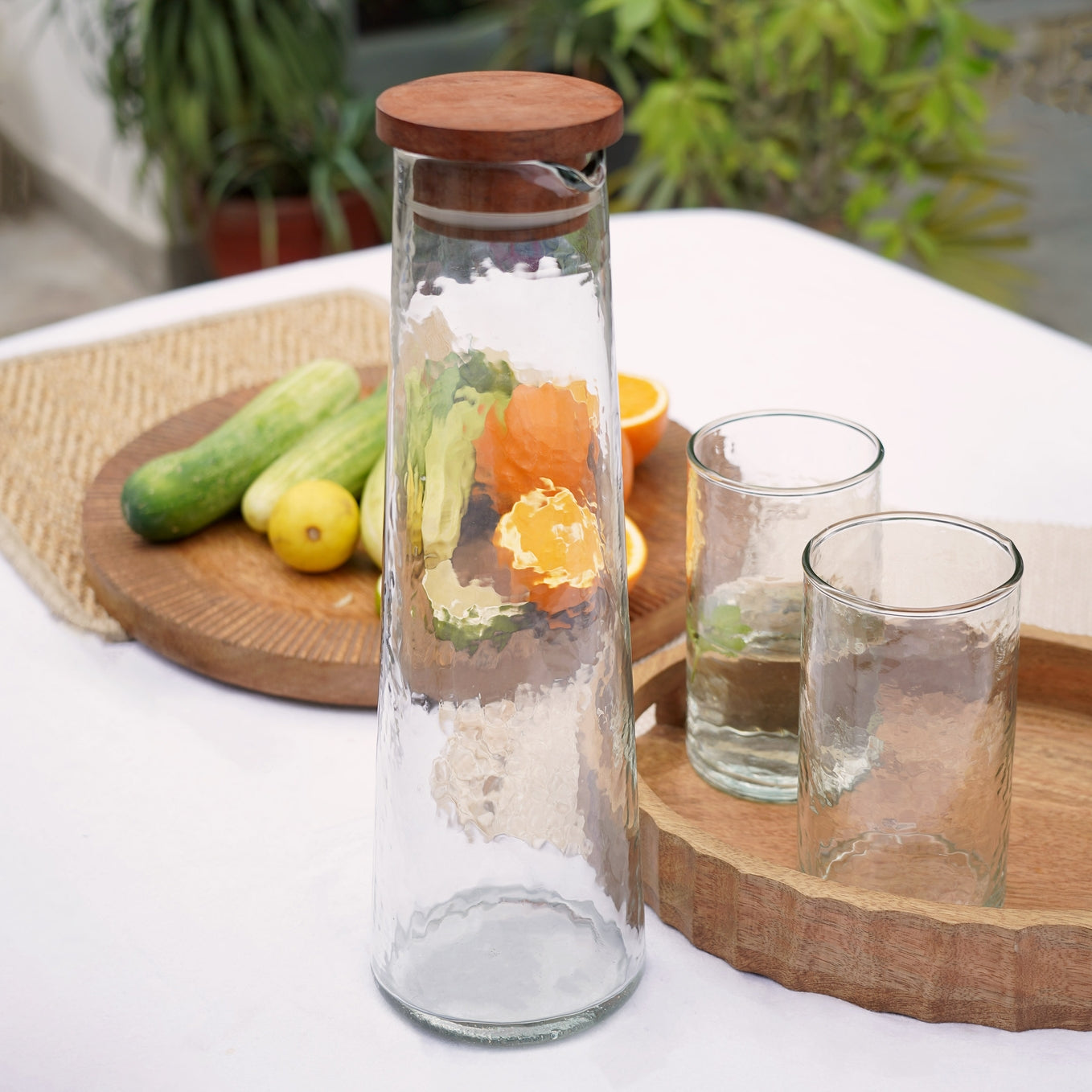 Crafted from premium non-toxic glass to preserve the authentic taste, this set features a mesmerizing hammered texture. The addition of a high-quality wooden lid ensures the integrity of your drinks, making it a functional and stylish choice. Hand blown glass skillfully handcrafted in India.